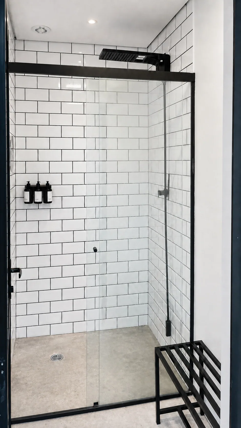 Vestiário da Kuadra com chuveiro, revestimento branco e acabamento preto